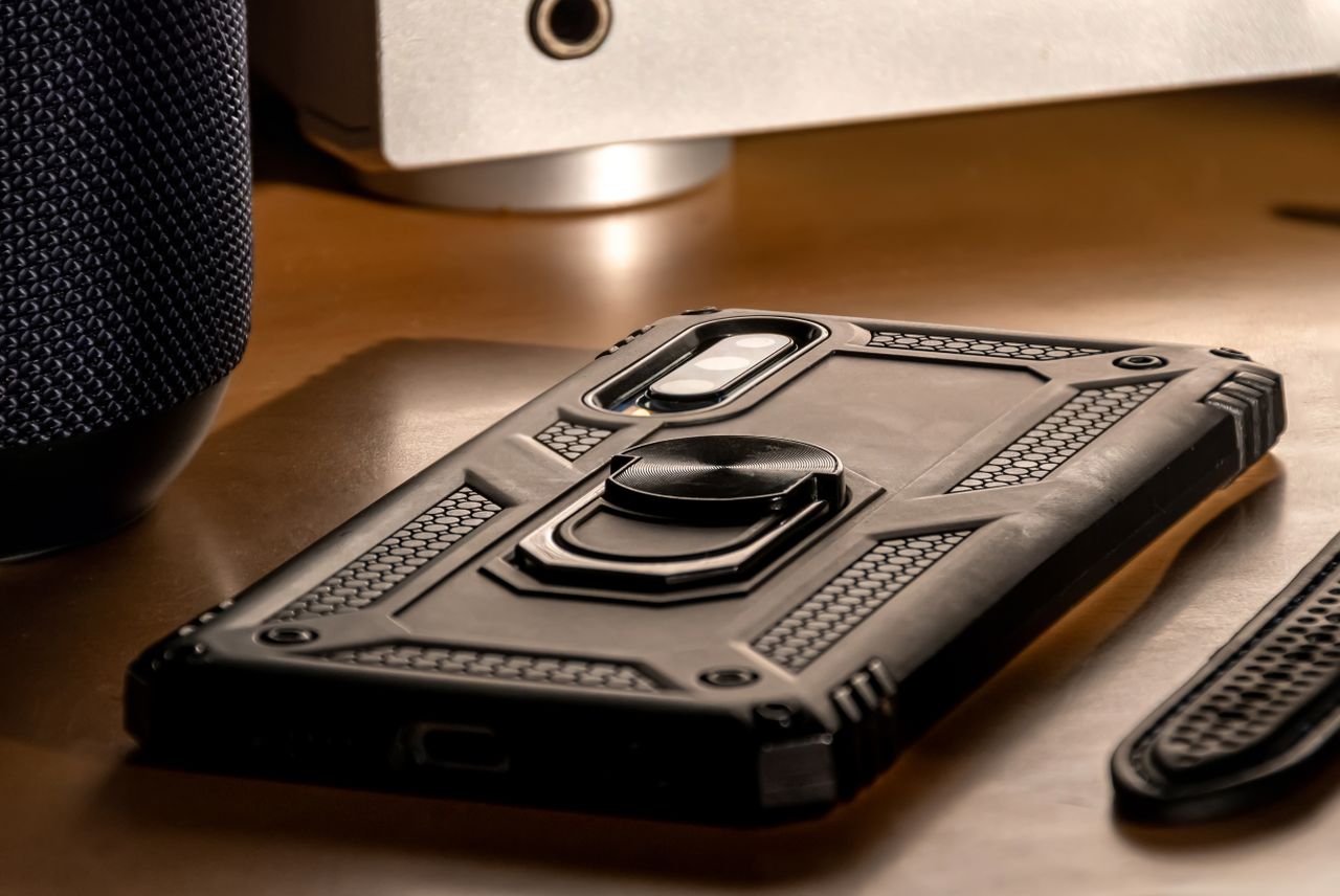 A detailed close-up view of a smartphone with a rugged case lying on a desk, showcasing modern technology.