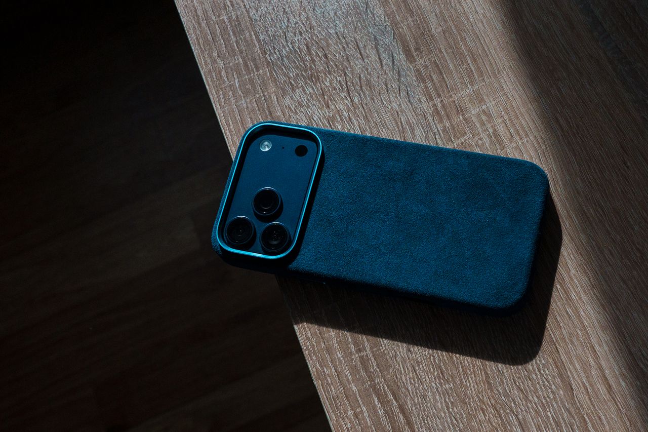 Dark smartphone case resting on a wooden surface, emphasizing modern design and minimalism.